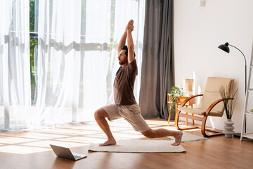 Middle aged, Latin man practicing yoga indoors with online class guidance
