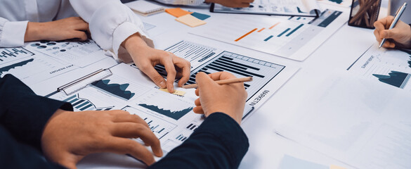 A diverse team engages in a collaborative financial analysis in a modern office. The workspace features charts, graphs, and data documentation, emphasizing teamwork and strategy. SACTR