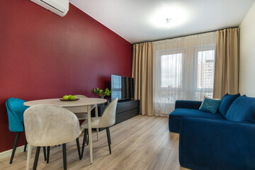 A living room with modern interior decor elements in a city apartment. Large window and cozy furniture.