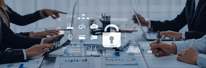 A professional team collaborates in an office setting, focusing on cybersecurity and data protection during a meeting. Digital graphics enhance the strategic discussion. Trope