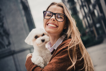 Young woman smiling with her dog in an urban setting on a sunny day