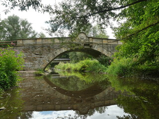 Historic baroque stone arch bridge near Erfurt-Molsdorf over the Apfelstädt river. Reflection in the river. Copyspace.