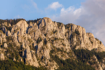 Majestic mountain cliffs bathed in late afternoon sunlight near a serene forest
