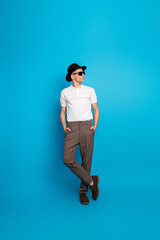 Young handsome man in stylish casual outfit posing against vibrant blue background exuding confidence and charisma