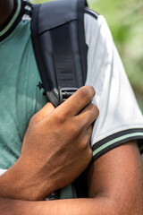 Close up of a persons hand holding a backpack strap