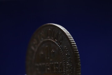 Close-up of a coin with a detailed edge and inscription, set against a dark blue background