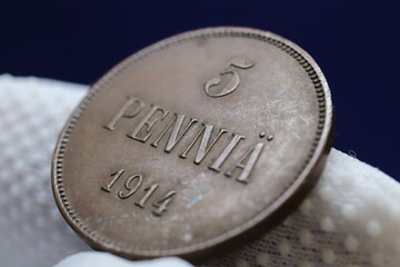 A close-up of a vintage coin with the inscription '5 PENNIÄ' and the year '1914'