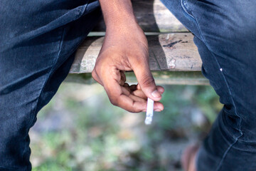 Closeup of a person holding a cigarette between their fingers