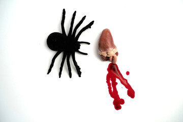 Black spider figure placed beside small organ with red blood drops on white background, creating...
