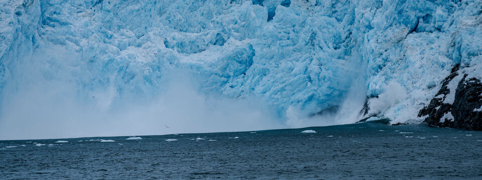 Calving action at Aialak Glacier causes a massive sea swell crashing into rocks