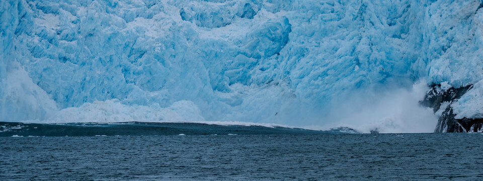 Calving action at Aialak Glacier causes a massive sea swell crashing into rocks