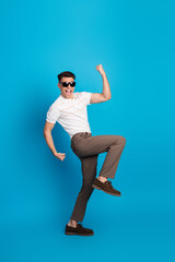 Obraz premium Energetic young man posing against a vibrant blue background, expressing excitement and happiness with dynamic gestures.