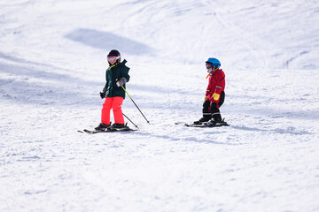 Children skiing downhill on sunny winter day