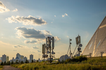 Tall communication towers are located near a modern building, surrounded by green grass under a...