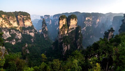 Stunning panorama of pillar-like mountains in a lush green valley with hazy background