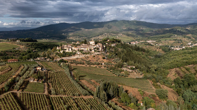 Aerial view of sun-kissed vineyards meet the ancient village perched atop a hill, where time seems to slow amidst the rolling Tuscan landscape, Greve in Chianti, Tuscany, Italy.
