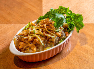 Shredded Chicken, Cucumber, Vermicelli, and Glass Noodle Cold Salad with Peanut Topping in ceramic dish on a wooden table side view of Asian food
