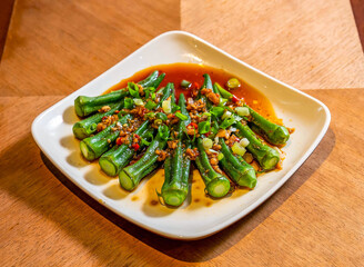 Chinese Cold Okra Salad with Garlic, Chili and Scallions Dressing in plate on Wood Table side view of Asian Cuisine