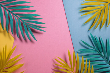 Colorful tropical leaves on pink, blue and yellow background in studio shot
