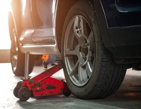 Car lifted on jack in a garage - Powered by Adobe