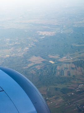 Fototapeta Aerial view of a patchwork of fields and forests fading into the misty horizon, seen from an airplane window, Warsaw, Masovian Voivodeship, Poland.