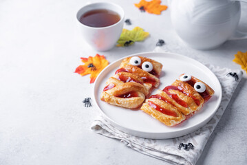Puffed cakes with raspberry jam in the form of mummy for Halloween holidays