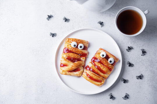 Puffed cakes with raspberry jam in the form of mummy for Halloween holidays - Powered by Adobe