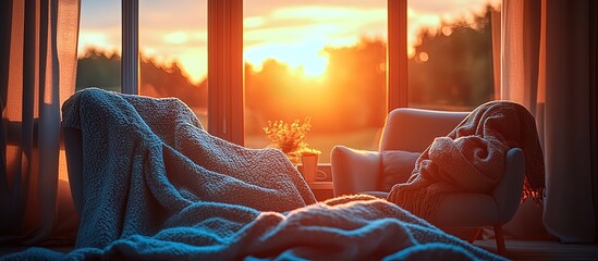 Cozy chairs draped with blankets bathed in warm sunset light by the window