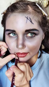 A beautiful girl with blue eyes in the frame, who gets scary makeup for Halloween