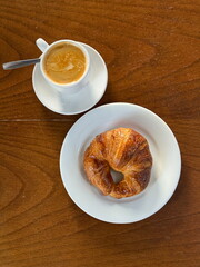 Delicious buttery croissant with hot coffee, simple continental breakfast setting on wooden background. Morning, brunch, tasty, cafe con leche, café au lait