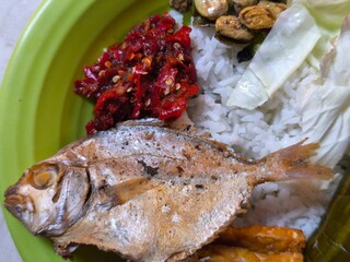 Traditional Indonesian meal with rice, fried fish, tempeh, and vegetables.