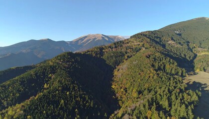 Panoramic view of forested mountains under a clear blue sky on a sunny day