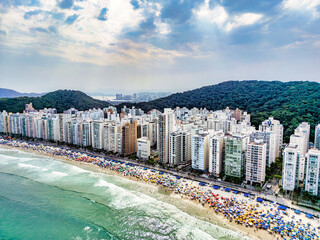 Vista aérea de dia ensolarado com muitos turistas na Praia de Pitangueiras no litoral paulista, Guarujá. 