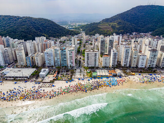 Vista aérea de dia ensolarado com muitos turistas na Praia de Pitangueiras no litoral paulista, Guarujá. 