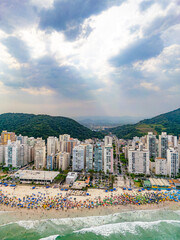 Vista aérea de dia ensolarado com muitos turistas na Praia de Pitangueiras no litoral paulista, Guarujá. 