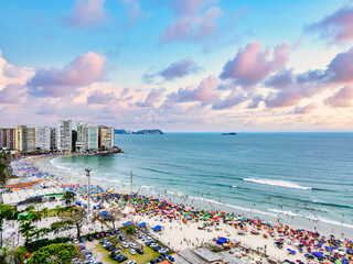 Vista aérea de dia ensolarado com muitos turistas na Praia de Pitangueiras no litoral paulista, Guarujá. 