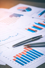 Business analysis: Pens lie on reports with charts and graphs. Strategic planning, financial review, and data interpretation are key.