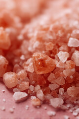Macro shot of delicate pink mineral crystals scattered across a flat surface, showcasing varied textures and subtle color variations.