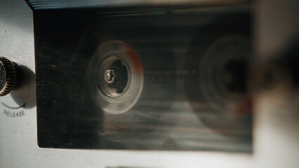 Macro retro cassette spinning across stereo heads in recorder. Magnetic tape