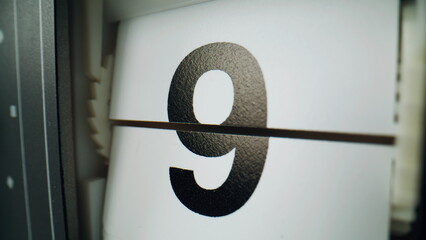 Flip clock changing numbers on white panels closeup. Macro view retro flipclock