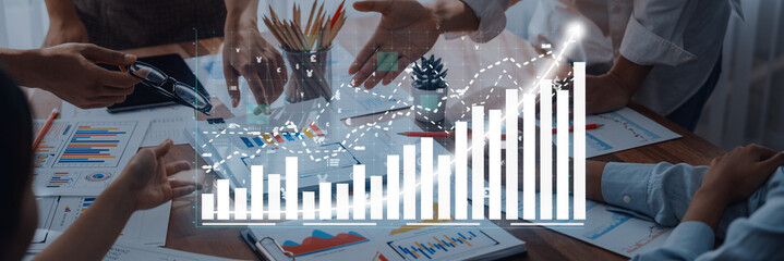 Business professionals engage in a collaborative meeting, discussing financial trends and growth strategies, surrounded by charts and documents in a modern office setting. Axiom