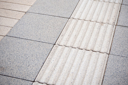 Tactile paving surface with raised grooves for blind guidance. Concrete textured tiles with accessibility pattern. Photo