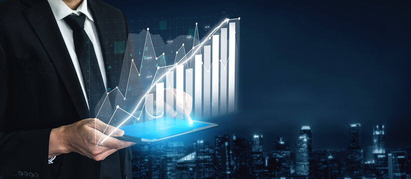 A businessman standing in a dark urban environment holds a tablet, showcasing a glowing data chart with line and bar graphs symbolizing growth and success. Impute - Powered by Adobe