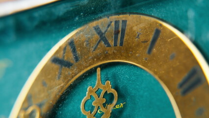 Macro beautiful vintage clock with figure metal hands at turquoise background.