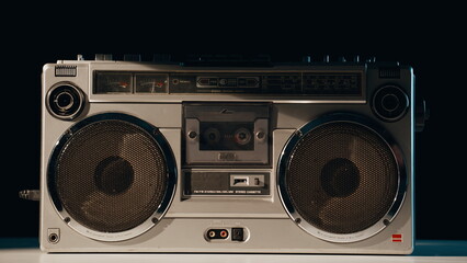 Fototapeta premium Hand pressing button boombox standing in evening light closeup. Listener turning