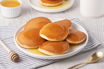 Delicious fluffy pancakes with syrup served on a white plate for breakfast