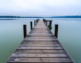 Tranquil Wooden Dock Extending into Calm Water Under Overcast Sky