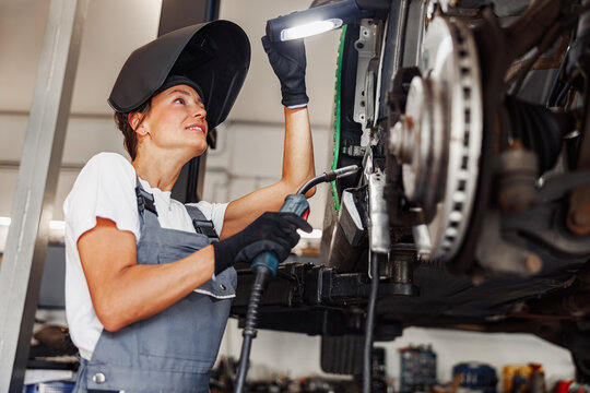 A highly skilled female mechanic expertly repairs a variety of cars using advanced welding equipment in a modern garage
