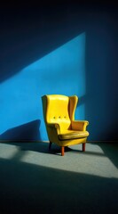 A vibrant yellow wingback chair casts a dramatic shadow against a deep blue wall, showcasing a simple yet striking interior design.