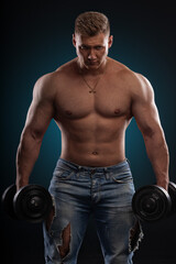 athletic man with a fit physique stands shirtless holding dumbbells in each hand. He appears...